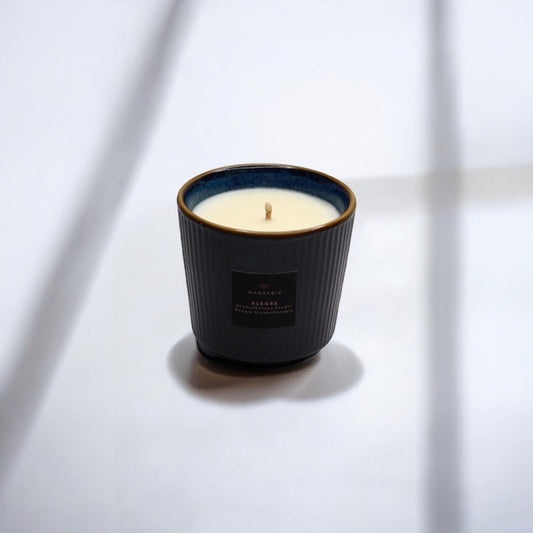 A close-up of an Alegre wellness candle on a surface