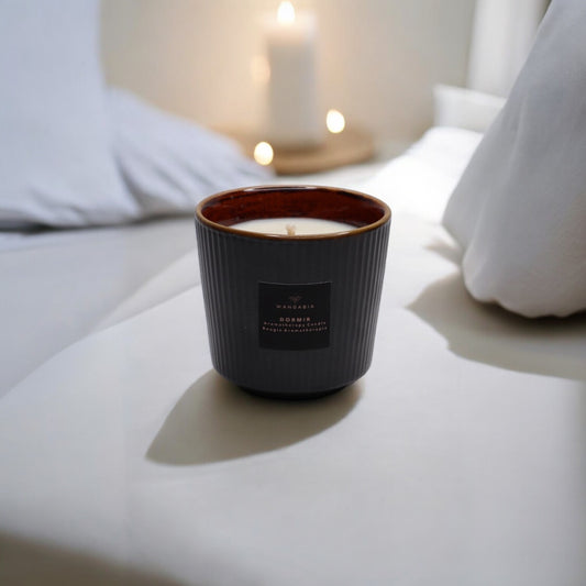 A Dormir wellness candle atop a surface with pillows in the background