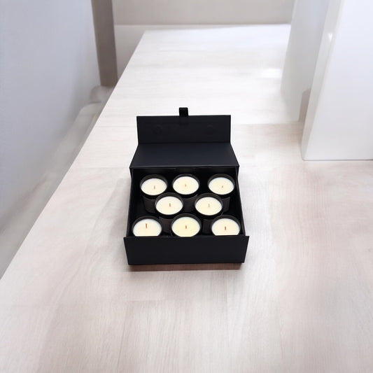 8 small candles in an open, black discovery set box on a table top